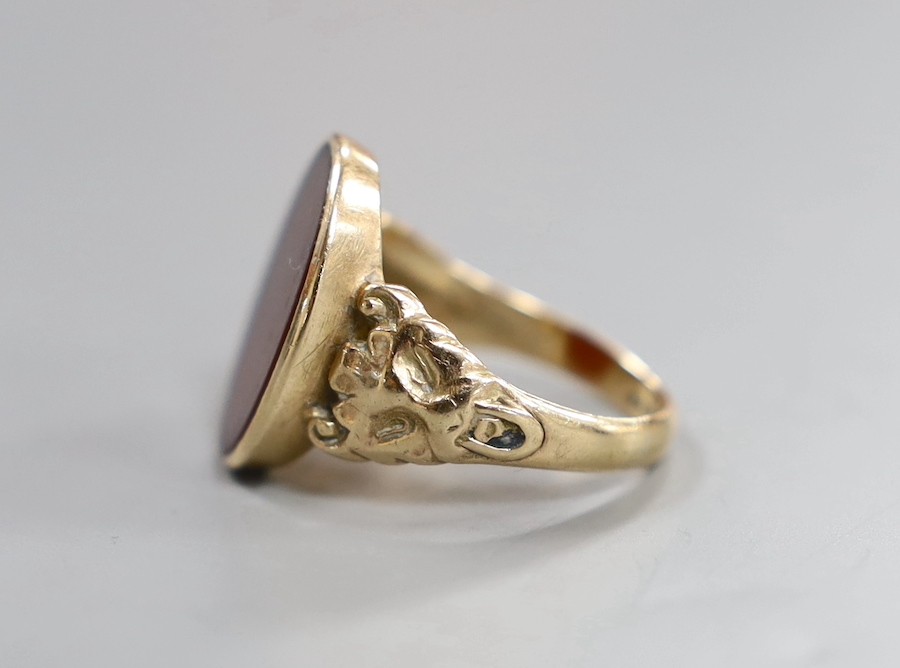 A 1970's Victorian style 9ct gold and carnelian set oval signet ring, with carved shoulders, size T, gross weight 6 grams.
